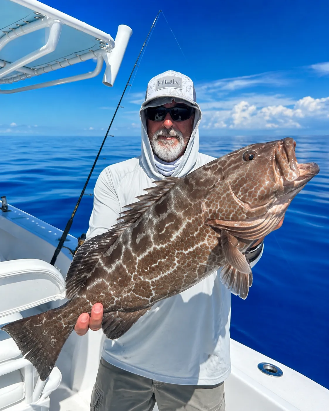 Angler holding a grouper brought up while bottom fishing